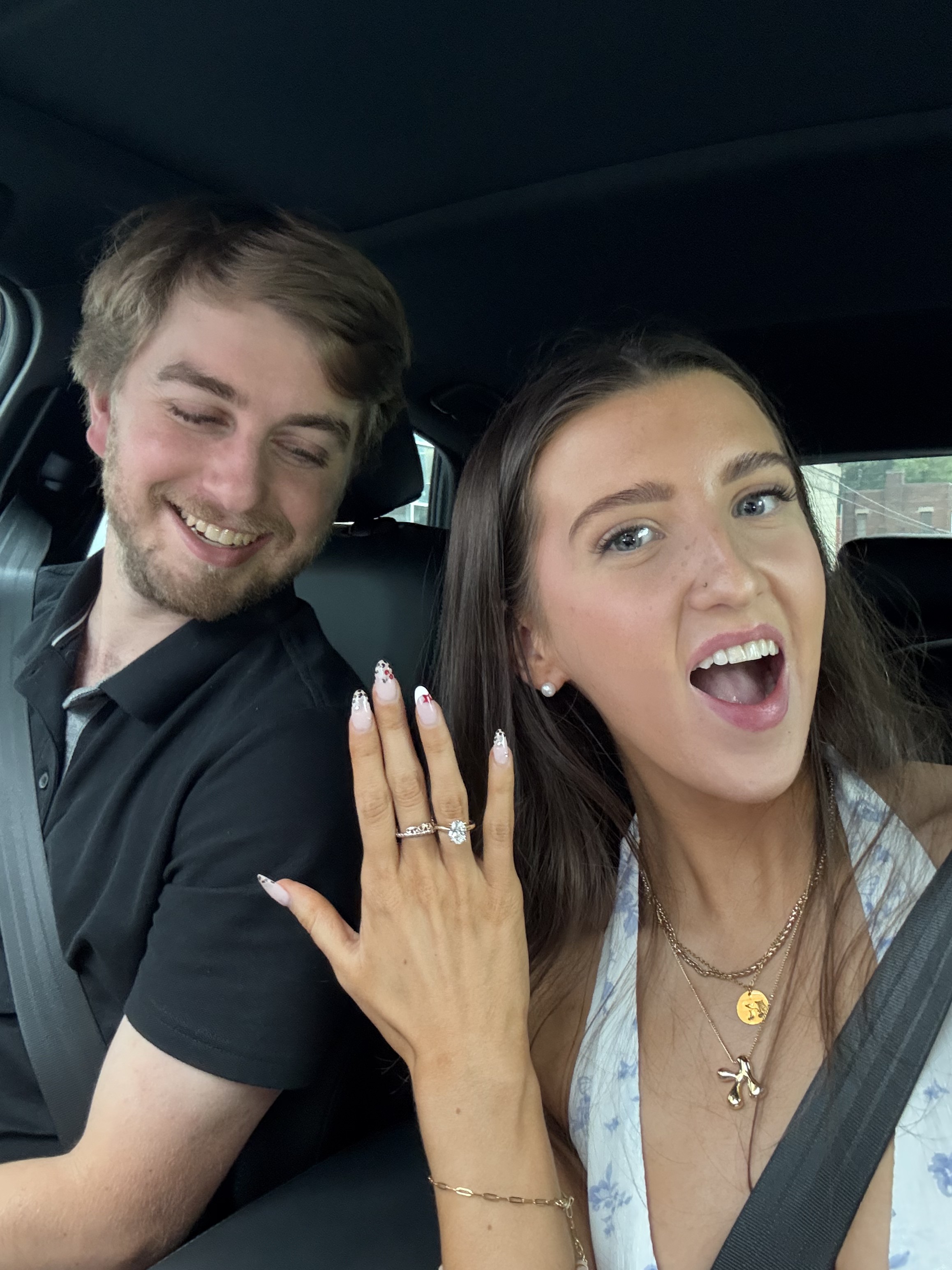 Kale Vine and Nick in the car, both looking shocked and smiling, engagement ring visible on her hand