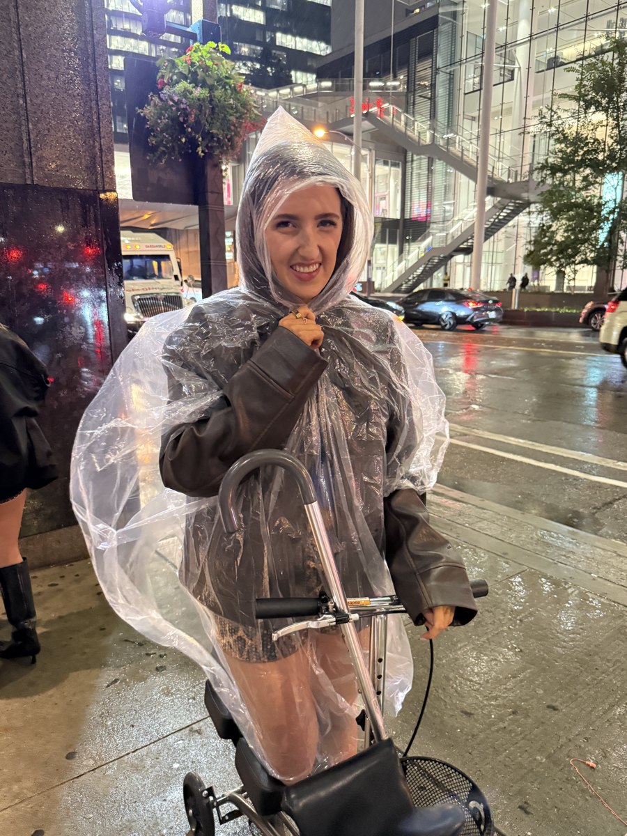 Kale Vine laughing on a Toronto street in a clear rain poncho at night